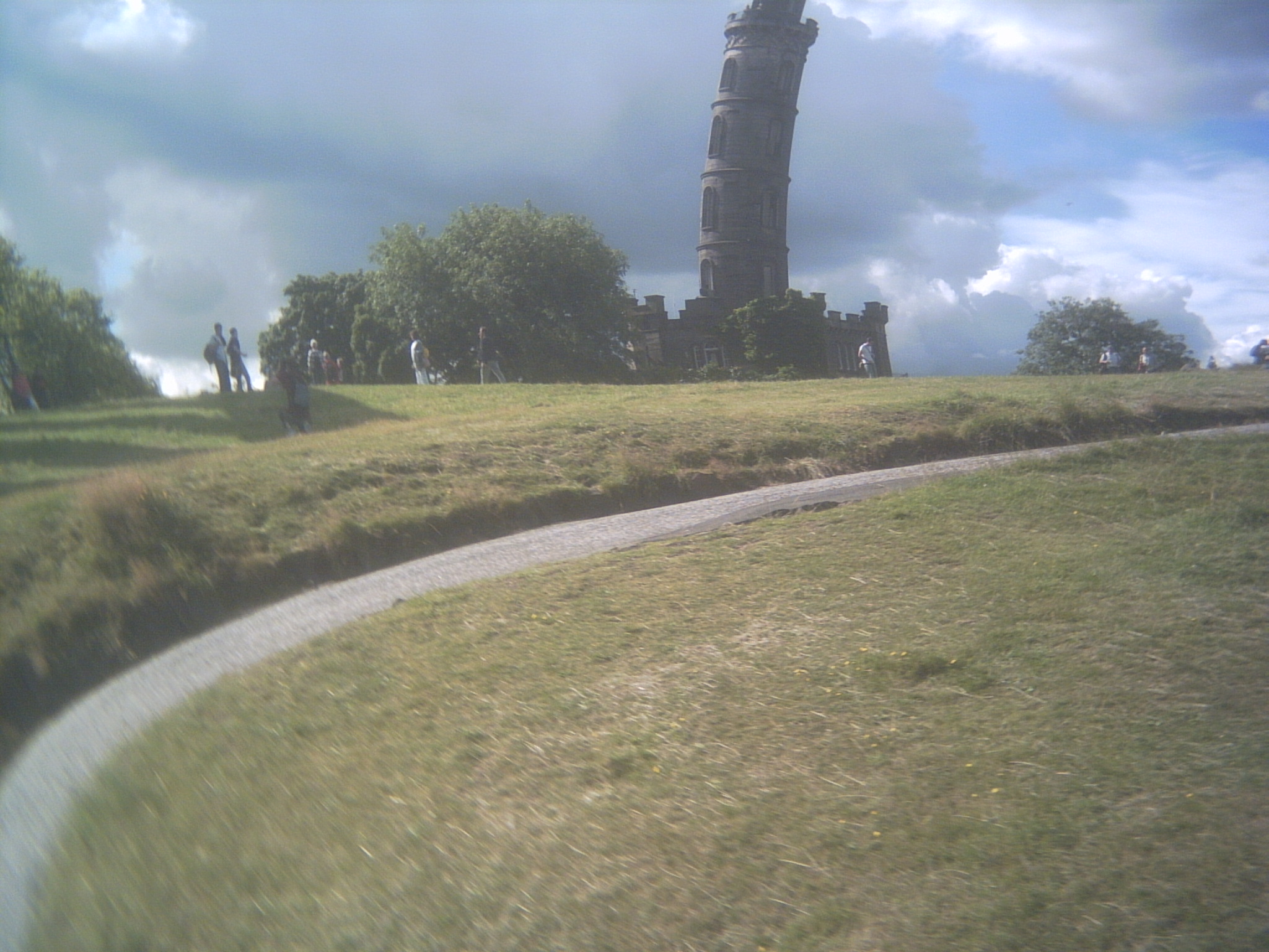 A view up Calton Hill in Edinburgh: most of the Nelson Monument, a cylindrical tower, is in view. The path leading up the hill cuts a swath across the image, from the lower left corner away to the middle right. The whole image is distorted: the tower curves to the right, and the path bends and blurs downwards at the left side of the image.